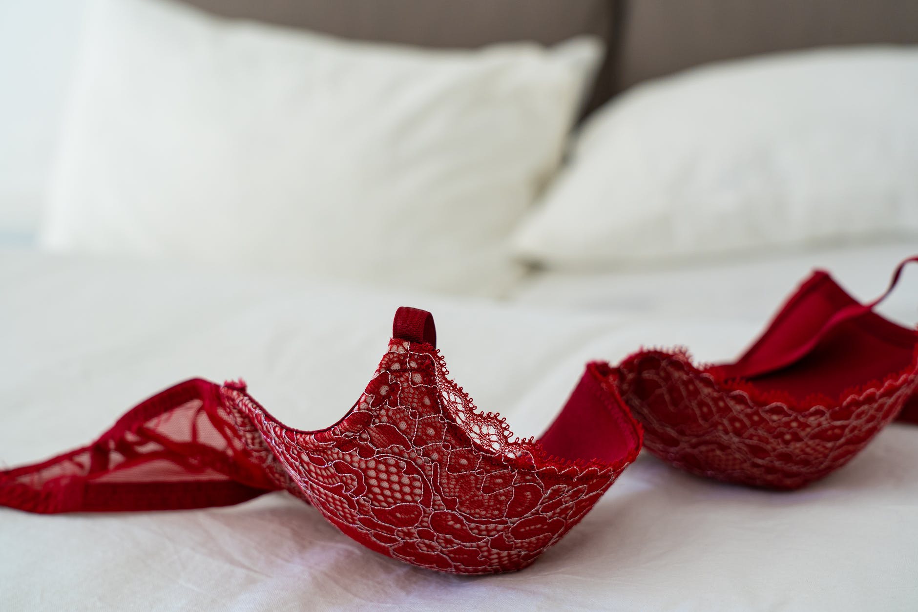 red lace brassiere on white bed